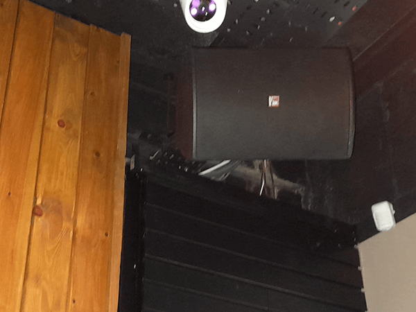 A black wall mounted loudspeaker installed as part of a full sound system in a bar in nottingham