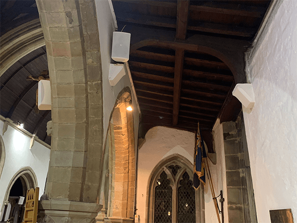 a white pa speaker wall mounted on to a church interior as part of an audio installation service