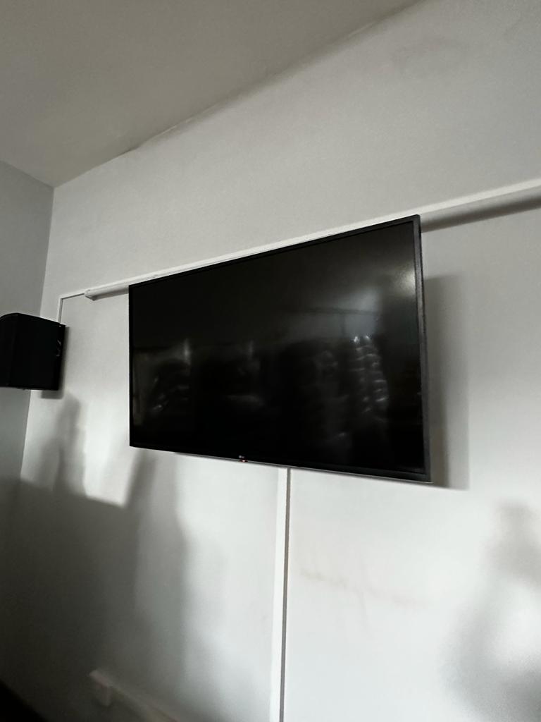 Wall mounted TV and black speakers as part of a church audio visual installation